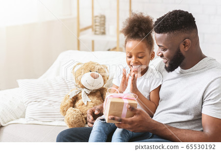 Excited black girl taking gift from daddy Excited black girl taking gift from daddy 65530192