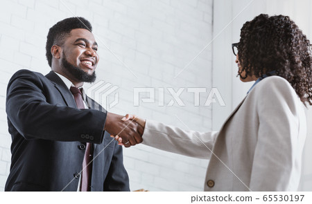 African American business partners shaking hands in office, making agreement 65530197