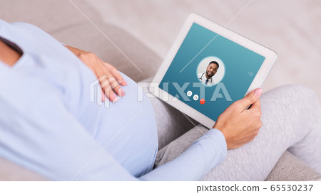 Woman having video chat with male doctor using tablet Woman having video chat with male doctor using tablet 65530237