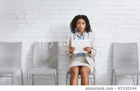 Beautuful black girl with resume being afraid of her employment interview in office. Space for text 65530244