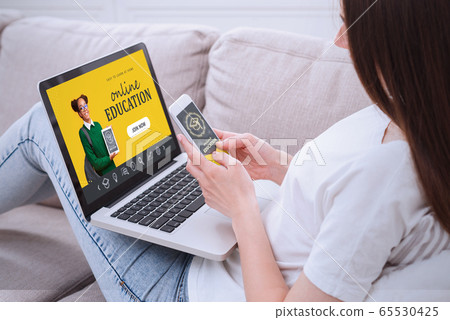 Young girl with smartphone and laptop computer browsing online education options at home Young girl with smartphone and laptop computer browsing online education options at home 65530425