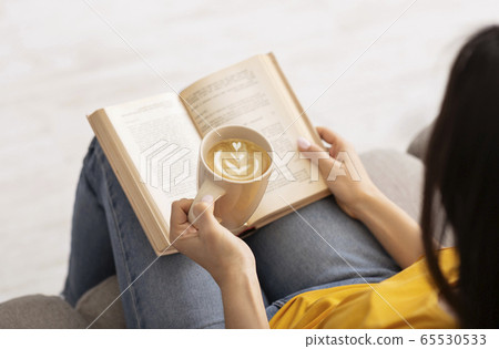 Stay home pastimes. Unrecognizable woman enjoying hot coffee and reading exciting book, indoors 65530533