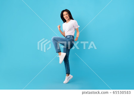 Happy woman jumping and looking at camera Happy woman jumping and looking at camera 65530583