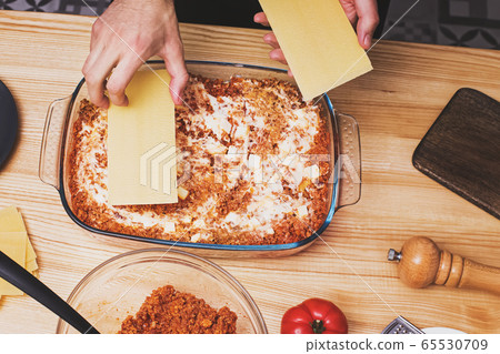 Man's hands making layers of lasagna in glass tray, Man's hands making layers of lasagna in glass tray, 65530709