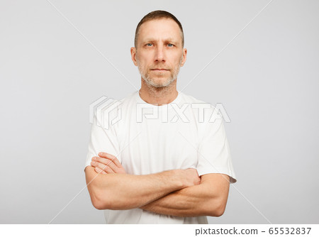 Man in white t-shirt with arms crossed on white background. Man in white t-shirt with arms crossed on white background. 65532837
