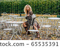 Young blond girl sitting at table in public park 65535391