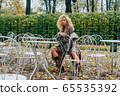 Young blond girl sitting at table in public park 65535392