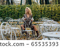 Young blond girl sitting at table in public park 65535393