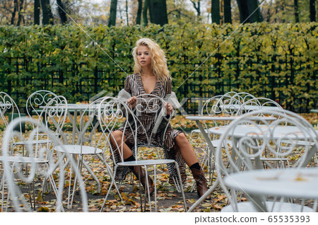 Young blond girl sitting at table in public park 65535393