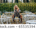Young blond girl sitting at table in public park 65535394