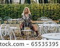 Young blond girl sitting at table in public park 65535395