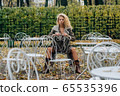 Young blond girl sitting at table in public park 65535396
