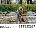 Young blond girl sitting at table in public park 65535397
