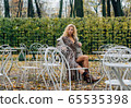 Young blond girl sitting at table in public park 65535398