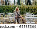 Young blond girl sitting at table in public park 65535399