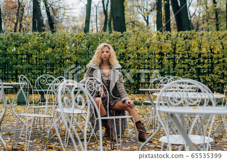 Young blond girl sitting at table in public park 65535399