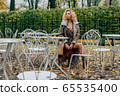 Young blond girl sitting at table in public park 65535400