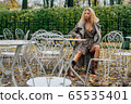 Young blond girl sitting at table in public park 65535401