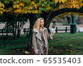 Young blond girl walking in public park in fall 65535403