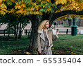 Young blond girl walking in public park in fall 65535404