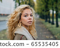 Young blond girl walking in public park in fall 65535405