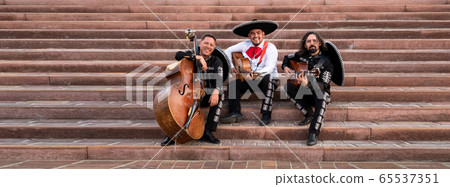 Mexican musicians play musical instruments in the city. City street in the summer. 65537351