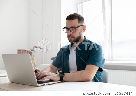 Confident bearded businessman typing on keyboard using laptop. 65537414