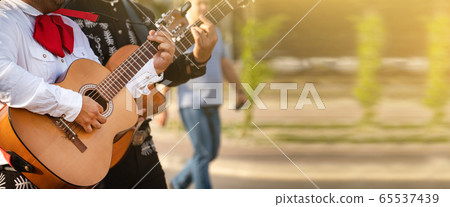 Mexican musicians play musical instruments in the city. City street in the summer. Mexican musicians play musical instruments in the city. City street in the summer. 65537439