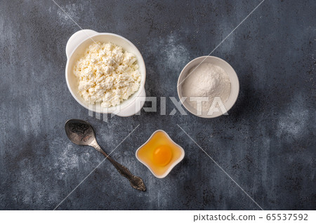 Ingredients for making homemade cheesecakes - cottage cheese, flour, egg. Bakery background. Top 65537592