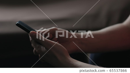 Closeup young man in black t-shirt typing messages on smartphone working from home side view Closeup young man in black t-shirt typing messages on smartphone working from home side view 65537866
