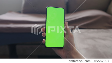 Closeup young man sit on a couch and show smartphone with green screen Closeup young man sit on a couch and show smartphone with green screen 65537907