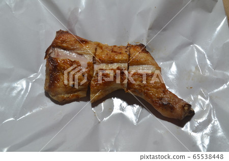 Pieces of grilled chicken in a container. 65538448