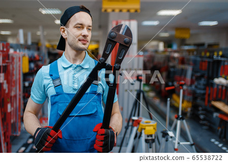 Worker holds big metal wire cutters in tool store 65538722