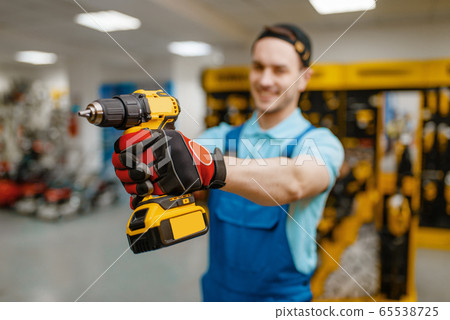 Male worker holds battery screwdriver, tool store 65538725