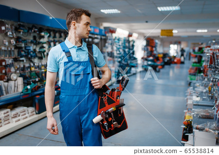 Male worker in uniform holds toolbox in tool store 65538814