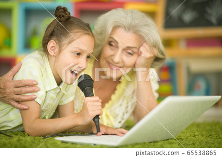 Grandmother and daughter singing karaoke with laptop Grandmother and daughter singing karaoke with laptop 65538865