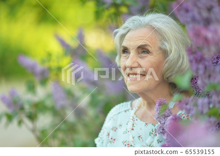 Happy senior beautiful woman on lilacs background 65539155
