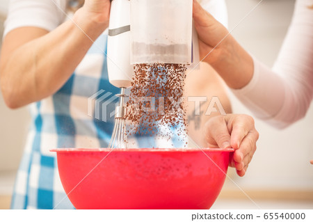 Detail on hand of two women putting chocolate 65540000