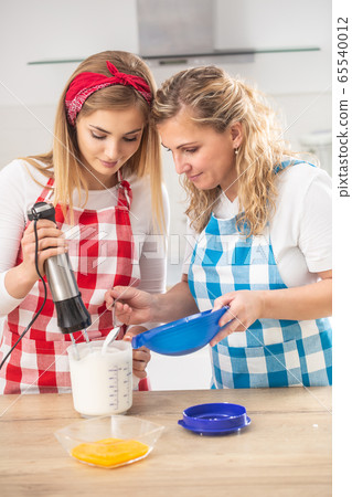 Blonde mother helps daughter with baking in the Blonde mother helps daughter with baking in the 65540012
