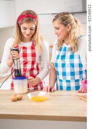 Mother helping daughter in teh kitchen, with the 65540015