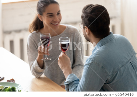 Happy young couple drink wine enjoy date in home kitchen 65540416