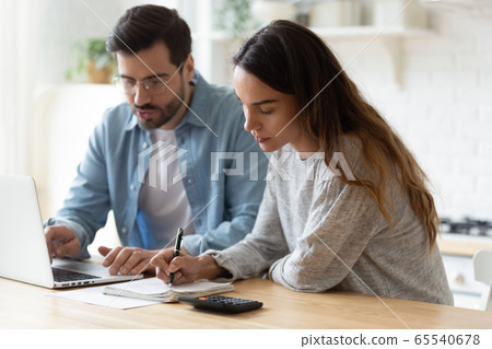 Young couple paying bills online at laptop at home 65540678