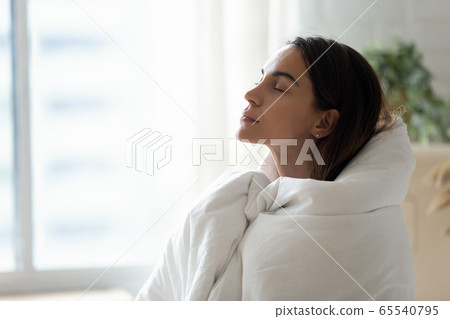 Young woman relax ta home warming up in blanket 65540795