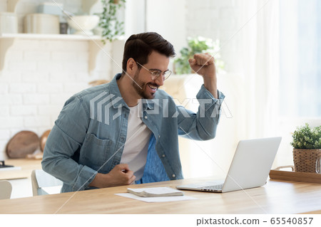 Excited man feel euphoric reading good news on laptop 65540857