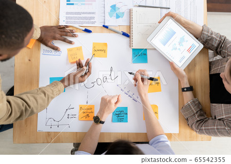 Top view of three intercultural managers or analysts discussing business goals Top view of three intercultural managers or analysts discussing business goals 65542355