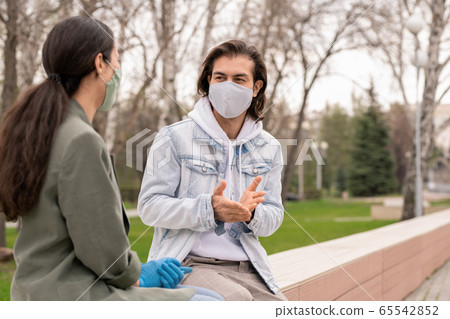 Young man and his girlfriend in protective masks discussing something Young man and his girlfriend in protective masks discussing something 65542852