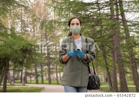 Young brunette woman in protective gloves and mask looking at you Young brunette woman in protective gloves and mask looking at you 65542872