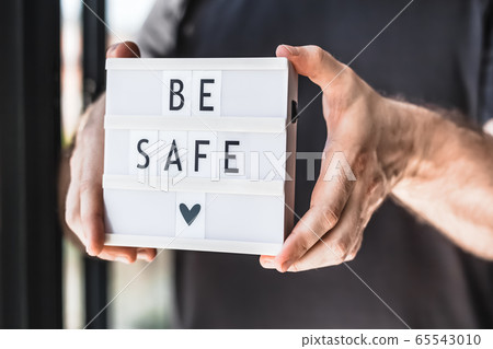 Man holding lightbox with text Be safe in his hand 65543010