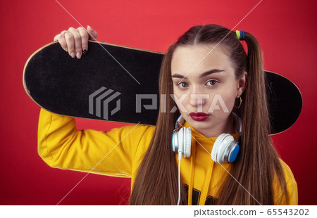 Teen colorful female with headphones and skateboard 65543202