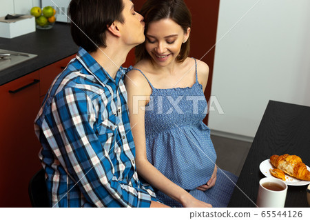 Caring young man kissing pregnant woman in forehead Caring young man kissing pregnant woman in forehead 65544126